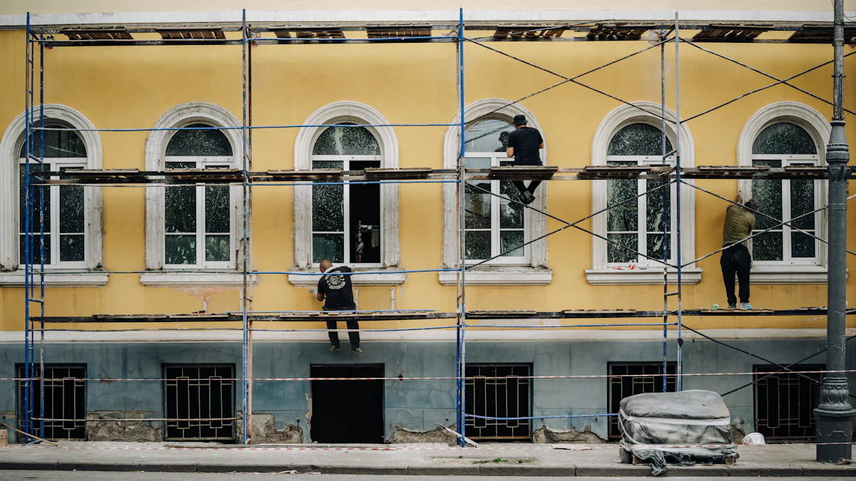 Façadiers au travail sur un échafaudage devant une façade enduite jaune aux fenêtres cintrées