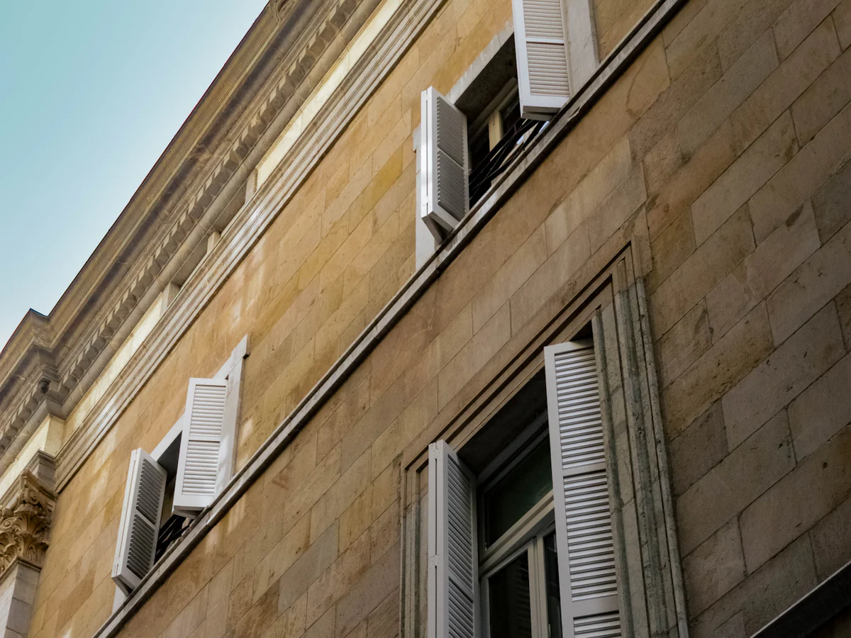 Façade en pierre claire avec volets blancs, avant nettoyage de façade